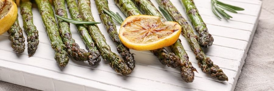 Overhead view of a platter with grilled asparagus spears garnished with lemon slices.