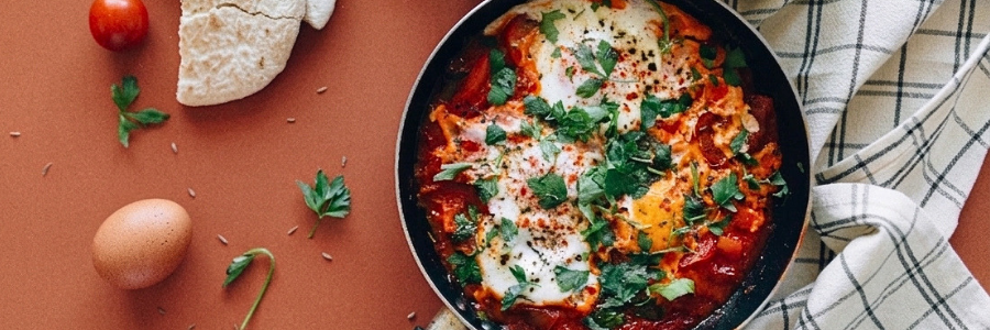Poached eggs with tomato sauce in a black skillet with fresh cilantro garnish