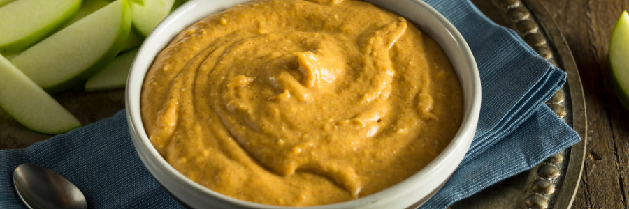 Overhead view of pumpkin pie dip in a bowl surrounded by apple slices.